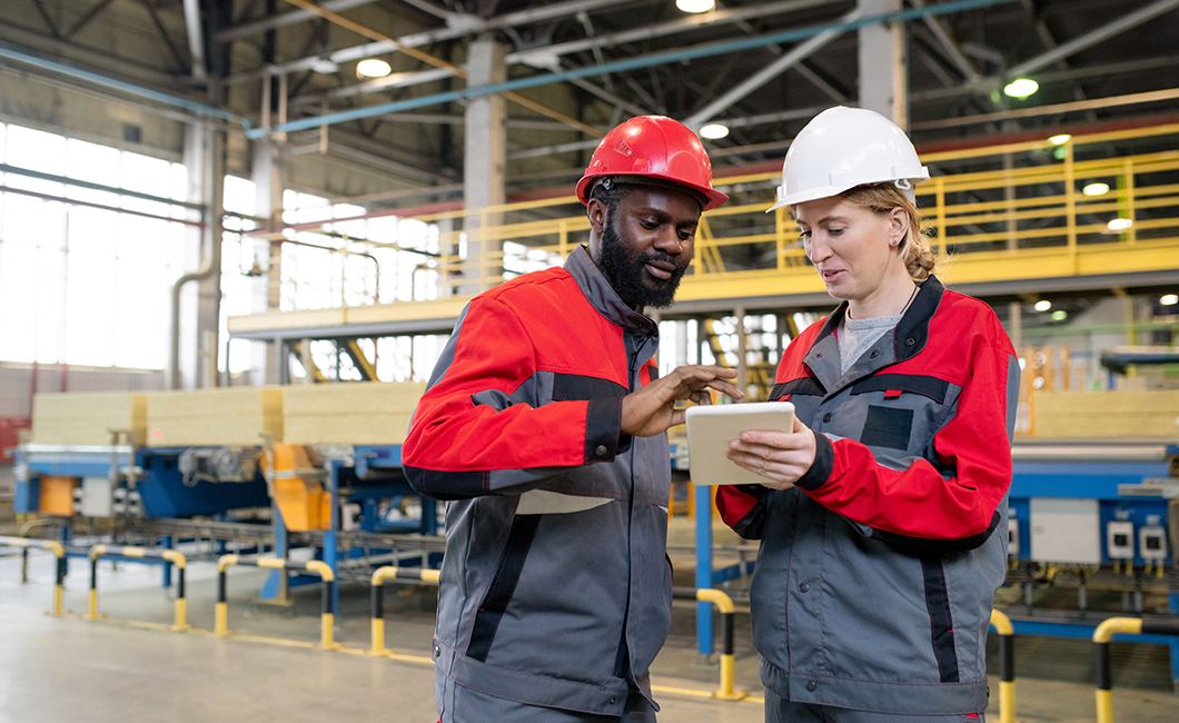 Two engineers reviewing production data on a tablet on the factory floor