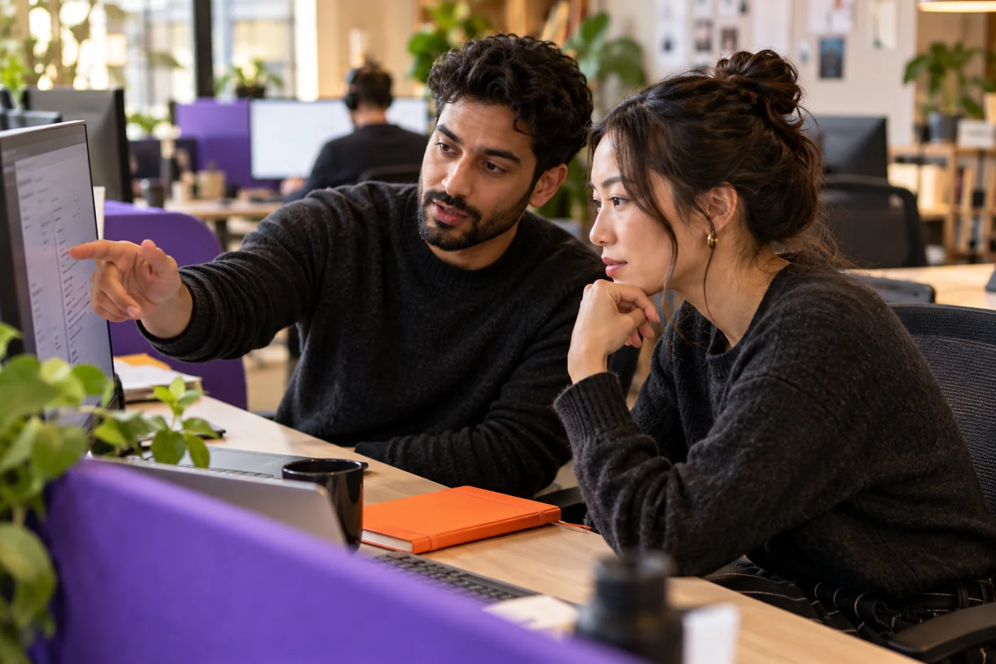 Illustrative scene of two support colleagues investigating an issue together, with violet and orange workspace accents.