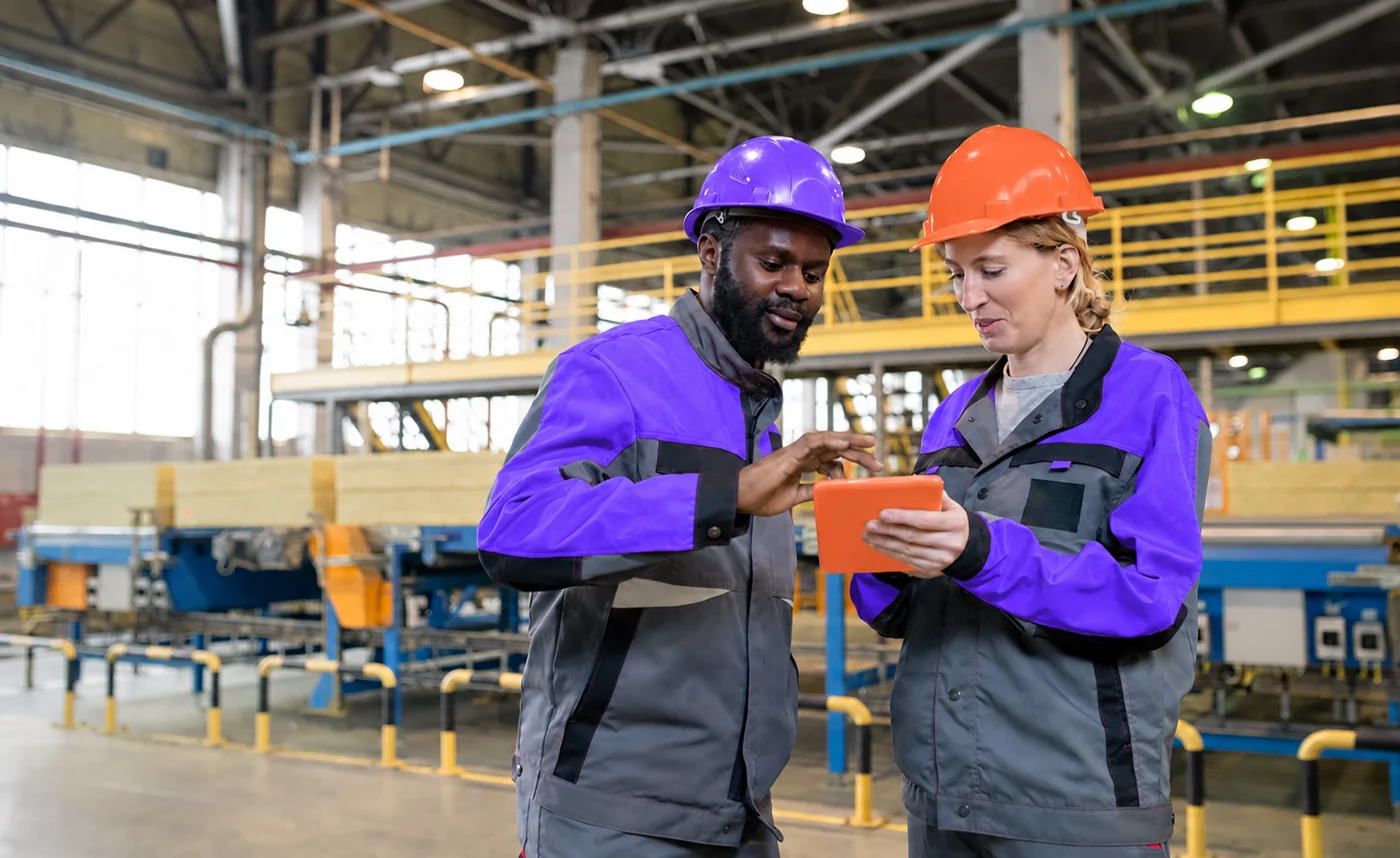 Two engineers reviewing production data on a tablet on the factory floor